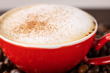 Lots of aromatic coffee beans with coffee in a red cup on a dark background