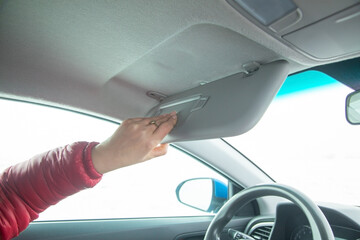 Female hand adjusting sun visor in a car.