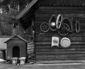 Ściana drewnianego domu z narzędziami rolniczymi i budą psa obok © kubikactive