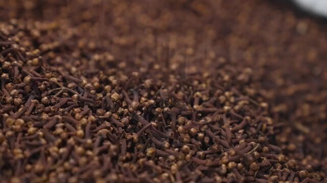 A large quantity of brown cloves are piled on a surface for display.