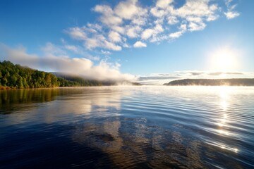 Obraz premium Mist Slowly Rising from Water Surface in Early Morning Light Over Calm Lake