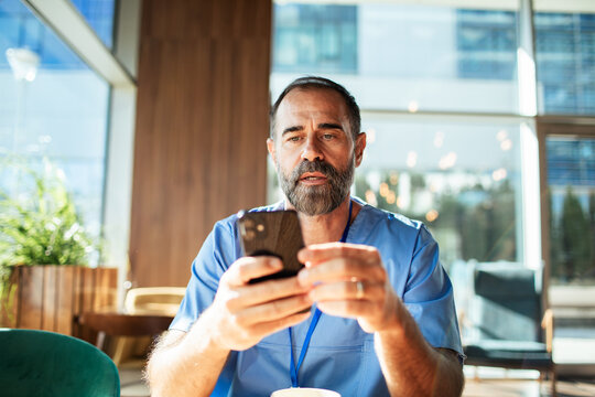 Male nurse using smartphone in hospital lobby