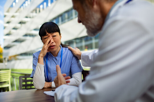 Doctor consoling stressed nurse outside hospital