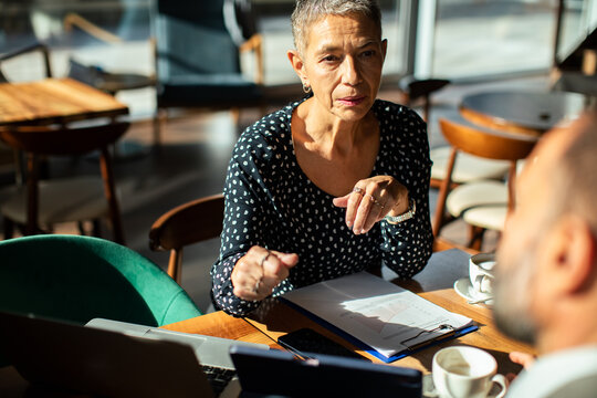 Senior businesswoman discussing financial report at cafe