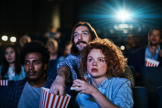 Friends watching a suspenseful movie in a crowded cinema