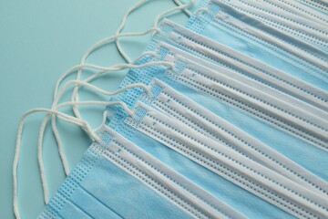 Blue medical masks covering the mouth and nose to protect against bacteria, on a blue background