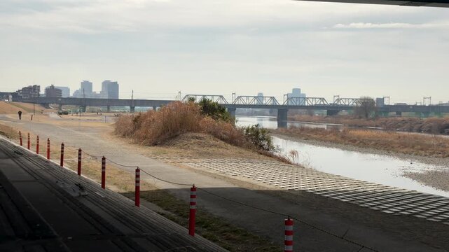 Urban riverside with railway bridge and city skyline in background