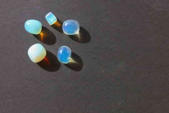 Opalite tumbled stones with prismatic light on black background