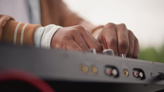 Side black DJ fingers tune mixer, quiet studio atmosphere with precise fader movement, visible ports and cables, focused sound engineering, measured levels and attentive producer technique.