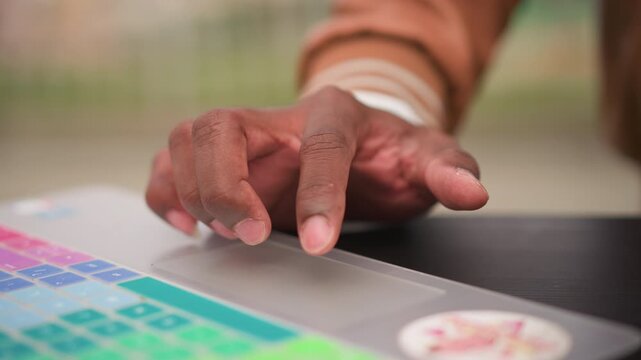 black producer fingertip on colorful pad, focused sample editing in park, morning sunlight on laptop, precise timing and subtle gestures, intimate creative session, tactile sound design.