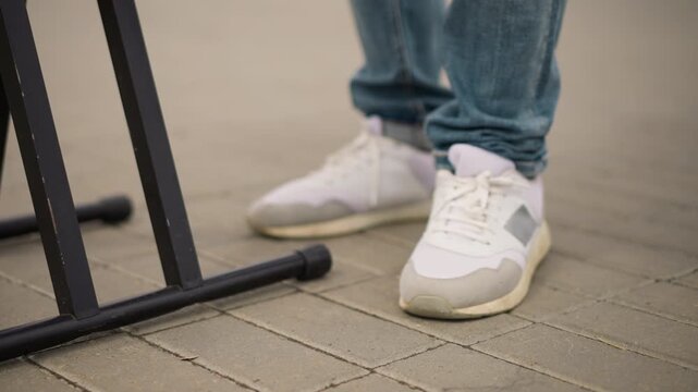 closeup sneakers near keyboard stand, unknown race musician tapping foot, denim jeans cuff, casual sneaker detail on city pavement, live outdoor busking vibe with subtle rhythm and movement