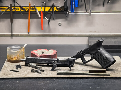 Baltic States, February 5, 2026: Disassembly and cleaning process of a Glock pistol on a workbench in a gunsmith workshop.
