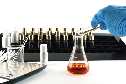 chemical science test tube , beaker or flask used on white table with blotting paper fragrance bottle and essential oil bottle used to blend nice scent for making perfume and candle by perfumer in lab