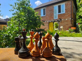 Group of wooden chess pieces are arranged on a table. There are five black pieces and five white pieces on village dacha