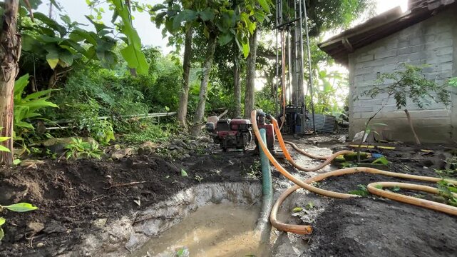 Water well drilling activity in a rural area using drilling equipment and hoses. This footage represents access to clean water, infrastructure development, groundwater exploration, and essential utili