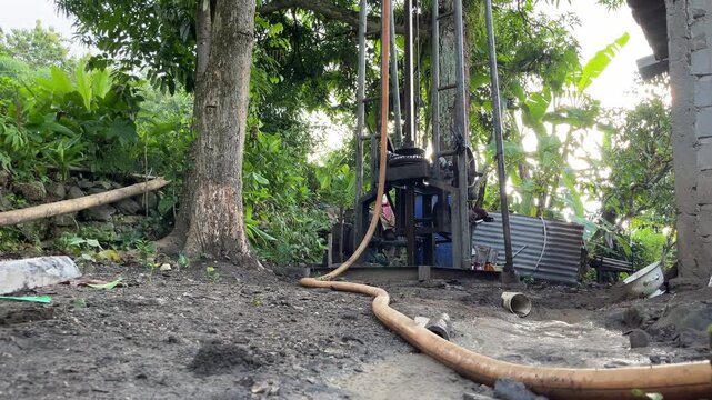 Water well drilling activity in a rural area using drilling equipment and hoses. This footage represents access to clean water, infrastructure development, groundwater exploration, and essential utili