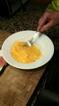 High view of woman hands whisking eggs with a fork.