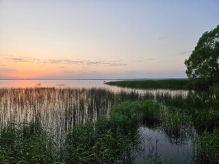 Lake with a sunset in the background. The water is calm and there are some trees in the background
