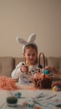Happy Little Girl in Bunny Ears Decorating Easter Eggs and Enjoying the Holiday