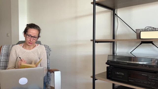 Mujer tomando notas en una libreta mientras teletrabaja