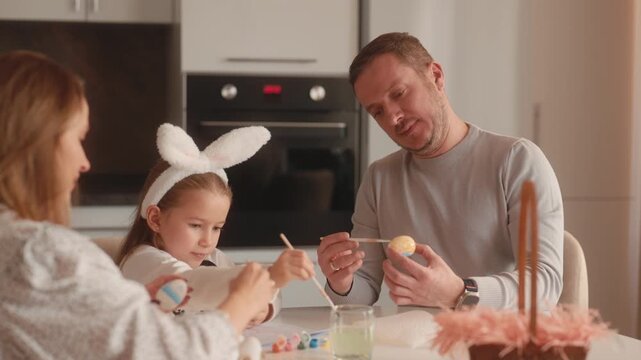 A Happy Family Paints Colorful Easter Eggs Together at Home, Celebrating the Holiday Season