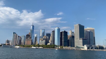 Obraz premium Lower manhattan skyline featuring one world trade center. Modern skyscrapers. And historic buildings rising above the tranquil hudson river under a clear sky