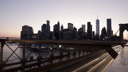 Metropolitan cityscape with brooklyn bridge steel trusses and long vehicle light trails linking vibrant dumbo to manhattan skyscrapers over the east river at sunset © DawDunia