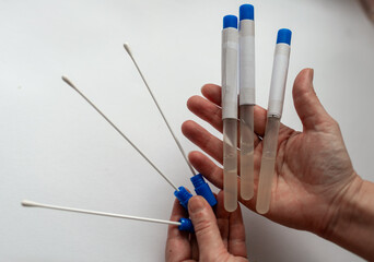Close up of hands presenting multiple sterile swabs and clear sample tubes with blue caps. Concept...