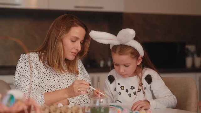 Mother and Daughter Painting Easter Eggs Together at Home for the Holiday Celebration