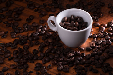 Coffee beans in white cup on wooden surface