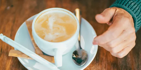 Fototapete Rund Cafe An elderly woman drinks hot coffee, hand and a cup closeup.  © Zhanna