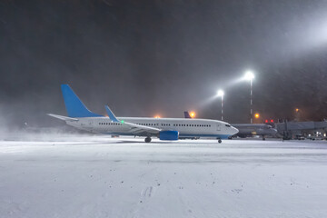 Taxiing of a passenger airplane at the airport in a snow blizzard at night
