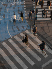 Pedestrians and bicycles gather crossing the street during the golden hour.  © Juan