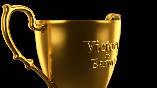 Golden trophy cup with Victory is Earned engraving on black background