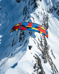 Paraglider soaring over snowy mountain peaks colorful wing extreme sport
