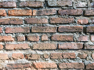 Naklejka premium Grungy Weathered Wall with Exposed Red Bricks and Aged Grey Mortar