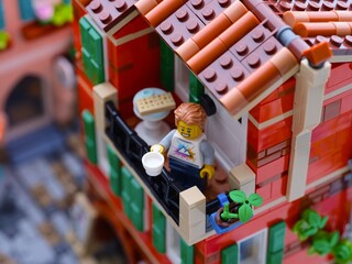 Obraz premium Tambov, Russian Federation - January 04, 2026 Lego man minifigure with white cup standing on a balcony in Mediterranean city.