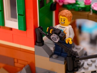 Obraz premium Tambov, Russian Federation - January 26, 2026 Lego man minifigure with camera standing on house porch outdoors