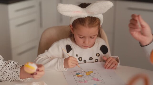 Happy Little Girl in Bunny Ears Painting Easter Bunny and Eggs with Family