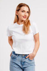 Obraz premium Smiling young woman posing in white t shirt and blue jeans for casual fashion concept