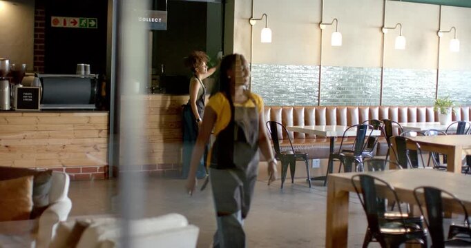 African American women in aprons in cafe walking after colleague passing, checking counter, seating