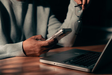Man Using Smartphone and Laptop at Work Desk