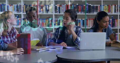 Sitting students in casual clothing discussing schoolwork at school library, with laptop and books