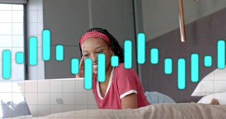 Lying woman wearing red tee, red headband propping elbows in bedroom viewing silver laptop waveform © vectorfusionart