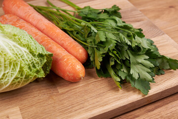 Ingredients for making salad, cabbage, carrots and parsley on a cutting board.