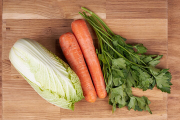 Ingredients for making salad, cabbage, carrots and parsley on a cutting board.