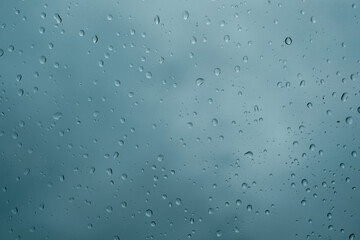Raindrops on the windshield during the rainy season. A landscape of raindrops on the gray glass.