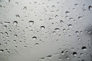 Raindrops on the windshield during the rainy season. A landscape of raindrops on the gray glass.
