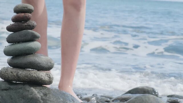 Children stack smooth pebbles stacked in balanced cairn, pyramid against ocean waves, Small hands playing with stones, Balanced stones on beach, summer holidays, travel, and serenity coastal retreats