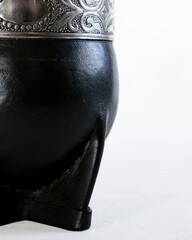 Traditional mate cup made from gourd covered with black leather and smooth metal rim, isolated on white background. Artisan South American drink container, product photo with copy space.